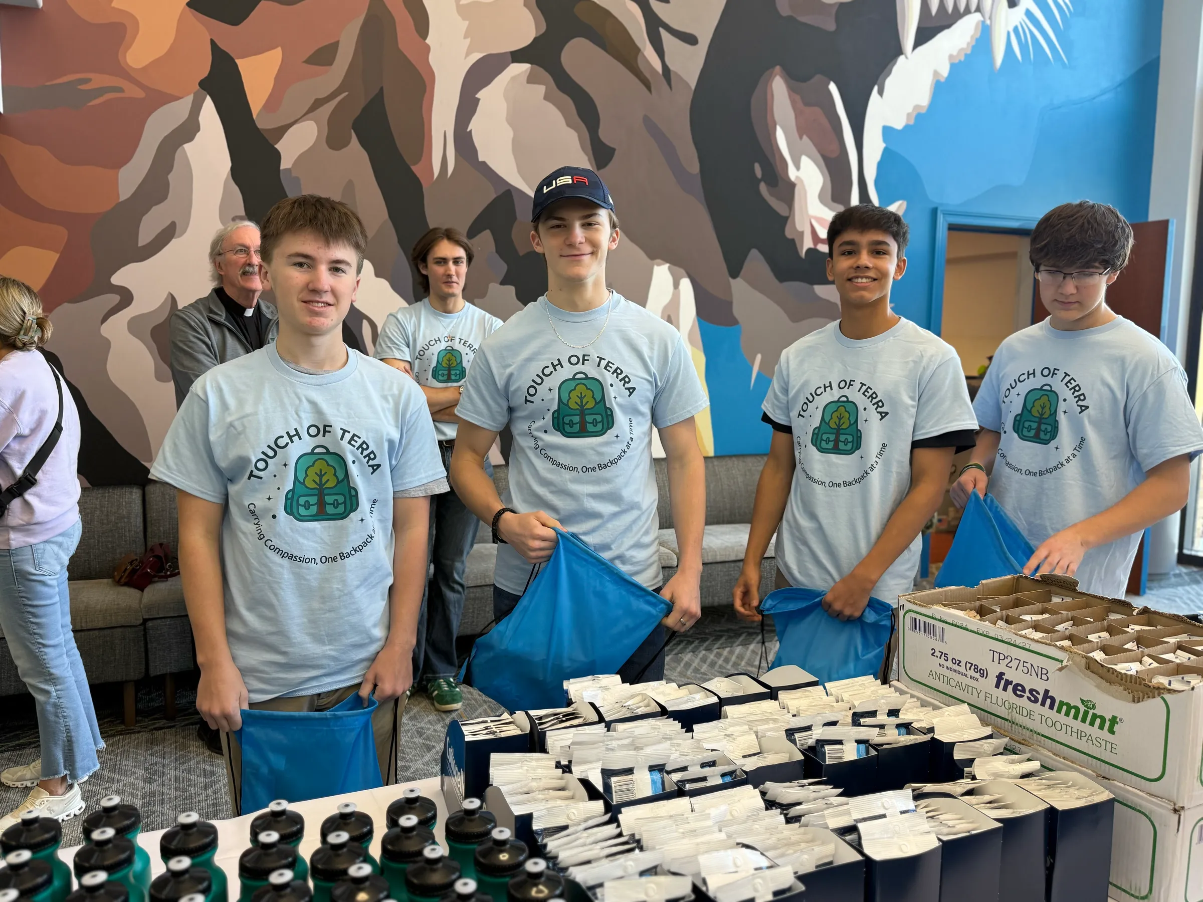 Four high-school students in Touch of Terra shirts packing supplies at a Pack-a-Thon.